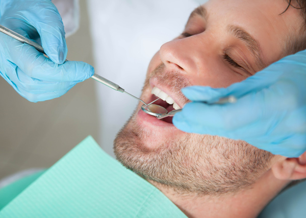 man receiving dental checkup with dental tools and gloves in a clinic setting focused on oral health and hygiene tips for healthy teeth and gums 9 dental care techniques