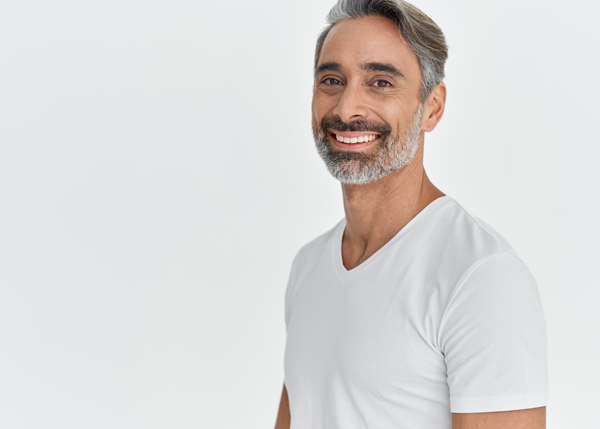 smiling middle aged man wearing a white t shirt standing against a light background showcasing confidence and happiness five key features