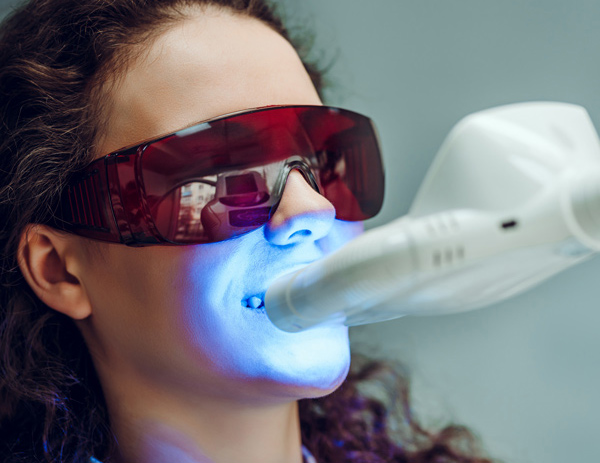 woman undergoing teeth whitening treatment with laser device wearing protective glasses in a dental clinic 2 treatments 2 sessions