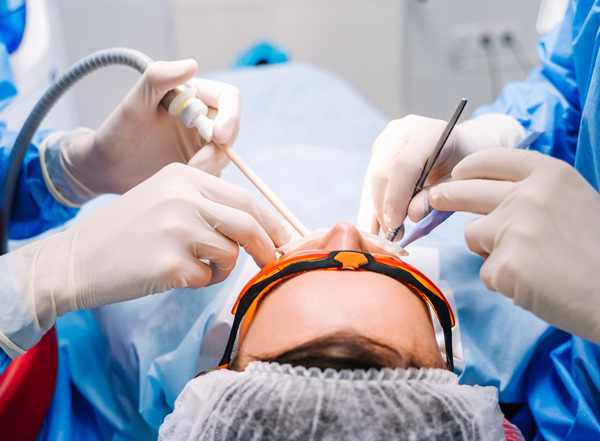 dental procedure with multiple instruments being used by professionals wearing gloves and protective gear focused on patient care and precision in dental health 2 procedures 2 clinicians