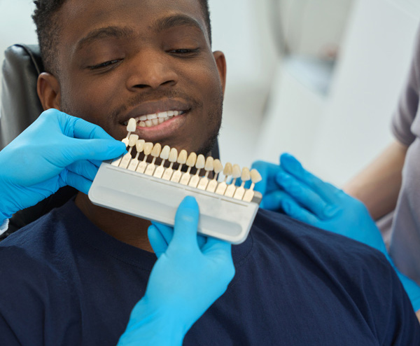 dentist examining patient smile with shade guide for teeth whitening and dental care options